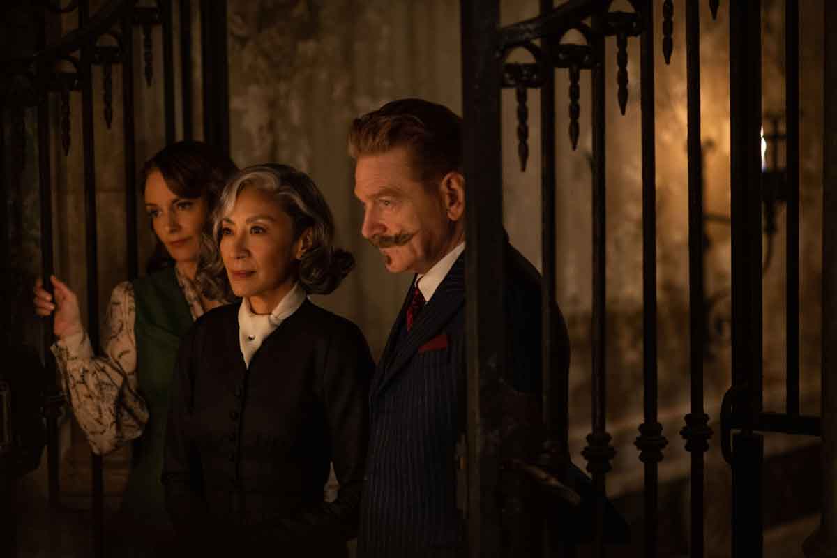 Tina Fey as Ariadne Oliver, Michelle Yeoh as Mrs. Reynolds, and Kenneth Branagh as Hercule Poirot in 20th Century Studios' A HAUNTING IN VENICE.